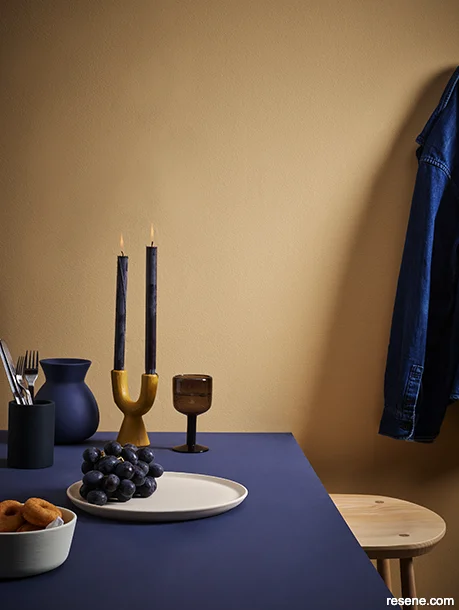 An interior with a painted deep blue table and ochre apricot walls