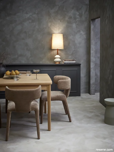 A dining room painted with moody hues and featuring layered neutral accessories