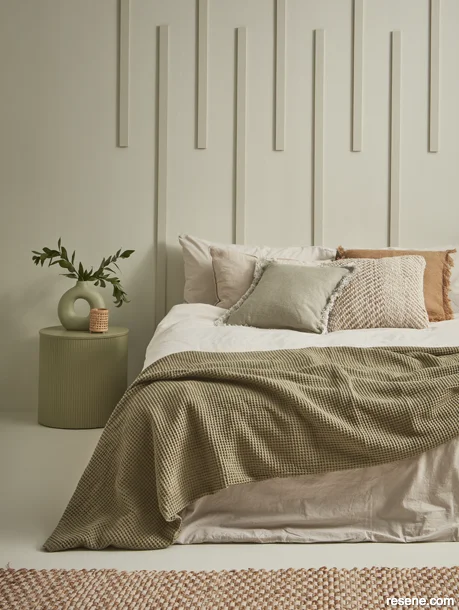A bedroom painted in muted green with decorative wall battens